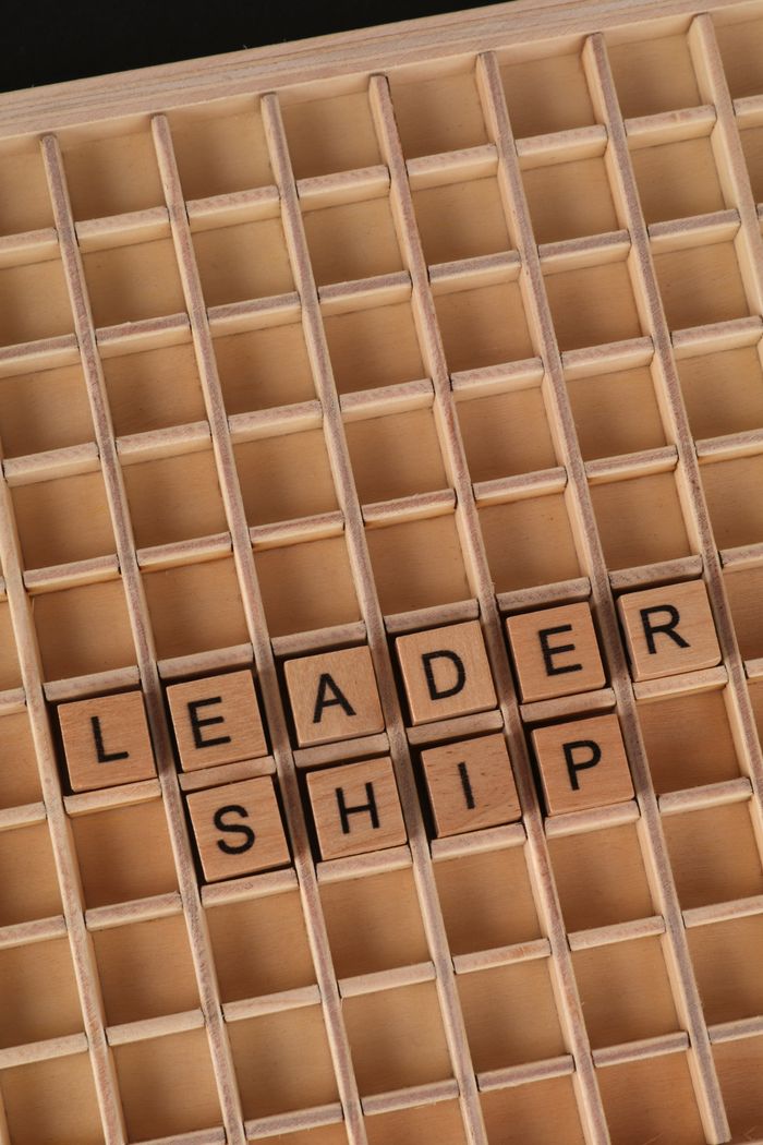 Home Wooden letter blocks spelling 'Leadership' arranged on a wooden grid background.
